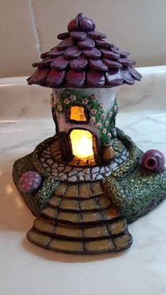 a small ceramic house with a lit candle in it