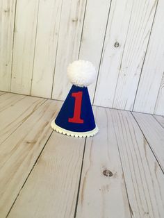 "Please read shop announcement for current processing times and updates. Your birthday boy will look absolutely adorable in this birthday hat for his first birthday or can be customized with any number! Perfect for a party or photo shoot. The hat is available in 2 sizes: Mini (5x4 inches) or full size (7x5 inches). It features royal blue felt and a red felt number 1. Mini pom pom trim is attached along the base of the hat with a white Pom Pom on top. It has an elastic chin strap to keep the hat Playful Blue Hat For First Birthday, First Birthday Hat, Boys First Birthday, First Birthday Hats, Mini Pom, Blue Party, High Chair Banner, Birthday Hat, Pom Pom Trim