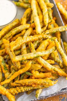 asparagus fries in a pan with dipping sauces on the side, ready to be eaten