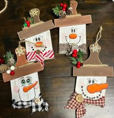 four snowmen are hanging from wooden boards