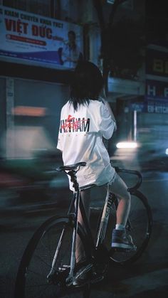 a woman riding a bike down a street at night