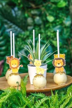 three small candles with animals on them are sitting on a tray in front of some plants