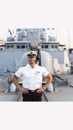 a man in uniform standing on the deck of a ship with his hands on his hips