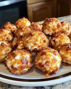 a white plate topped with cheese covered donuts on top of a kitchen counter next to an oven