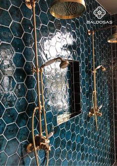 a bathroom with blue tiled walls and gold fixtures on the shower head, mirror, and faucet