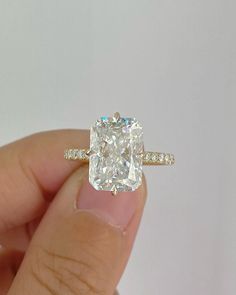 a person holding an engagement ring with a diamond in it's center and side stones around the band