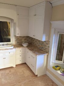 a large kitchen with white cabinets and marble counter tops, along with a window in the corner