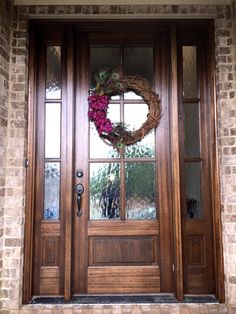 a wooden front door with a wreath on the top and side glass windows above it