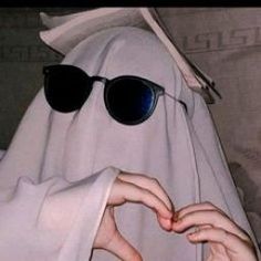 a person in a nun costume making a heart with their hands while wearing sunglasses and a veil