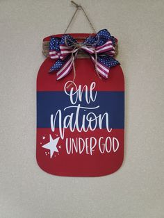 a red, white and blue sign hanging on the wall that says one nation under god