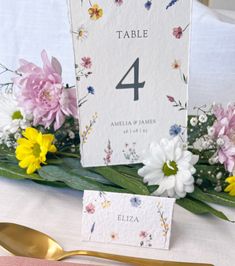 the table numbers are displayed with flowers and greenery on top of each place card