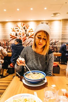 a woman sitting at a table with a bowl of soup