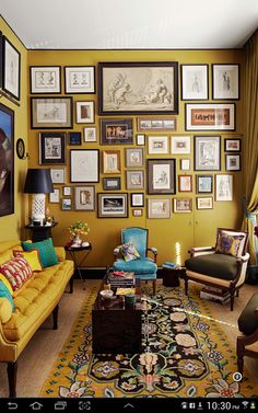 a living room filled with yellow furniture and pictures on the wall above it's coffee table