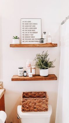 a bathroom with two shelves above the toilet and a basket on the back of the toilet