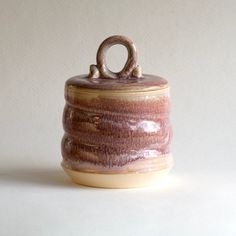 a brown and white ceramic container with an o on it's lid sitting on a table