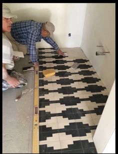 two men working on a black and white tile floor in a room that is being remodeled