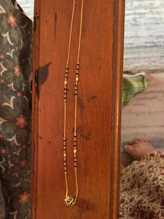 two necklaces are on display in a wooden box next to a woman's dress