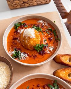 two bowls of soup with bread and parmesan cheese on the top one bowl has an egg in it