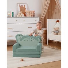 a baby sitting on a blue chair in a room with white furniture and teddy bears