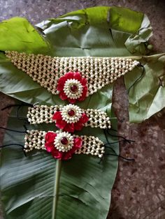 three red and white beaded flowers sitting on top of a green leafy plant