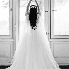 a woman in a wedding dress is looking out the window with her hands on her head