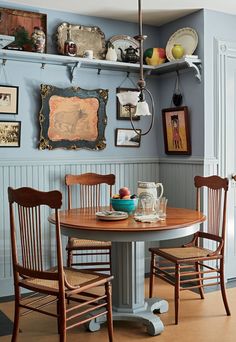 a dining room table with two chairs and pictures on the wall above it in an old fashioned kitchen