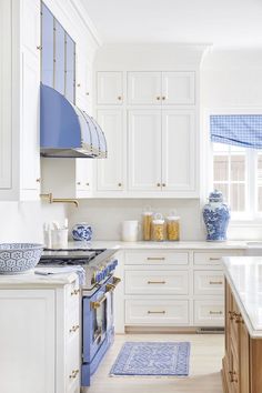 a kitchen with white cabinets and blue accessories on the counter tops, along with an area rug in front of the stove