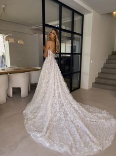 a woman standing in front of a doorway wearing a wedding dress with flowers on it