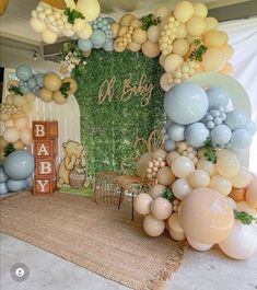 a baby shower is set up with balloons and greenery