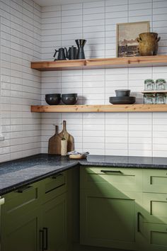 a kitchen with green cabinets and black counter tops, white tile backsplash and open shelving