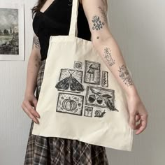 a woman holding a tote bag with drawings on it