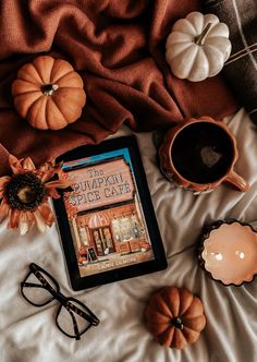 a book and some pumpkins on a bed with a cup of coffee next to it