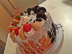 a large cake with cookies, cream and strawberries on top is sitting on a table