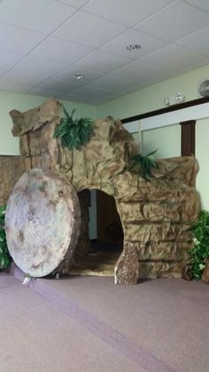 there is a large rock in the center of this room with plants and rocks around it