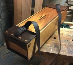 a wooden box sitting on top of a table with a leather strap around it's neck