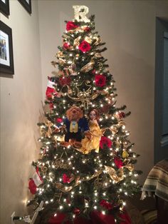 a small christmas tree decorated with red and gold ribbon, lights and teddy bear on top