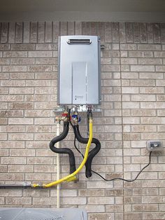 an electrical box attached to the side of a brick wall next to a yellow hose