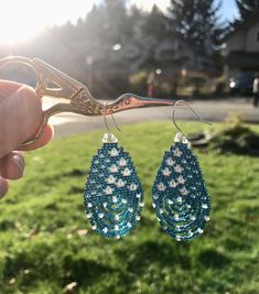 "\"Gentle Rain\" earrings remind us of the power of gentleness when we're caught in a storm. These take form as a raindrop, with an internal scene of translucent raindrops blossoming into flowers. Design features numerous faceted Labradorite gemstones that refract subtle rainbows of light, and encourage spiritual transformation, intuition, mental clarity and protection. Finished with elegant sterling silver ear-hooks. Including ear-hook, measures 2.5\" long, 1.25\" wide. Order includes inspirati Faceted Beads Teardrop Earrings Gift, Turquoise Teardrop Earrings With Faceted Beads, Gift Teardrop Earrings With Faceted Beads, Artisan Teardrop Beaded Earrings With Dangling Beads, Artisan Teardrop Earrings With Dangling Beads, Unique Handmade Teardrop Beaded Earrings, Teardrop Earrings With Faceted Beads For Gifts, Unique Teardrop Beaded Earrings, Teardrop Beaded Earrings For Jewelry Making