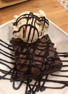 a piece of chocolate cake with ice cream on top and drizzled in chocolate