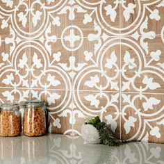 two jars filled with food sitting on top of a counter next to a tiled wall