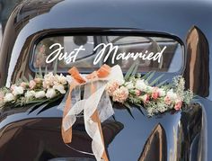 an old black car with flowers on the front and just married written on the side