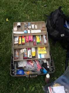 an open suitcase sitting on top of a lush green field filled with lots of items