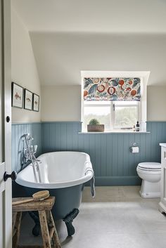 a bathroom with a claw foot tub, toilet and window in the wall above it