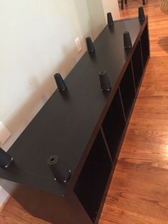 there is a shelf with several black objects on it in the room that has hardwood floors