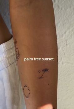 a person with a palm tree sunset tattoo on their arm and the words palm tree sunset written in white ink