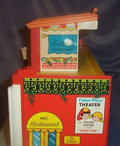 a red and yellow toy refrigerator sitting on top of a table