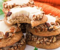 several cookies with white frosting and nuts are stacked on top of each other next to carrots