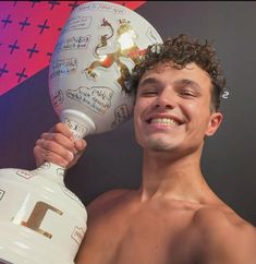 a shirtless man holding up a white vase with images on it's side