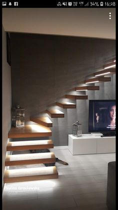 a tv sitting on top of a wooden shelf next to a stair case in a living room