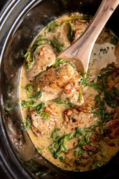 chicken and spinach soup in the crock pot with a wooden spoon inside it